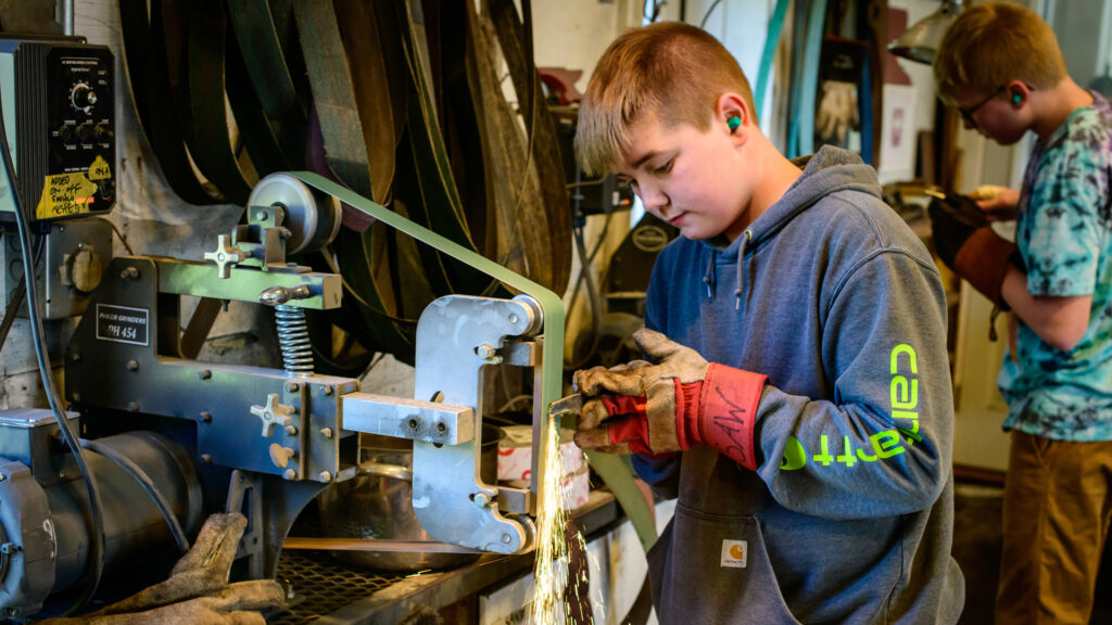 Young Student Grinding a Piece of Metal